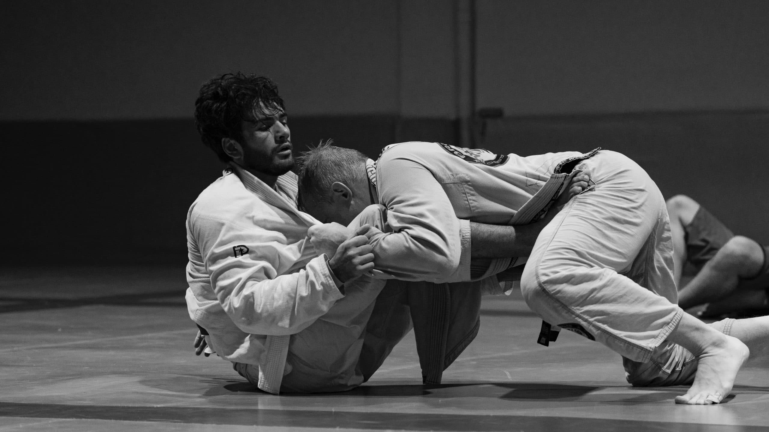 Zwei Erwachsene beim Brazilian Jiu-Jitsu im Gi auf der Matte im CHECKMAT-Studio Klagenfurt
